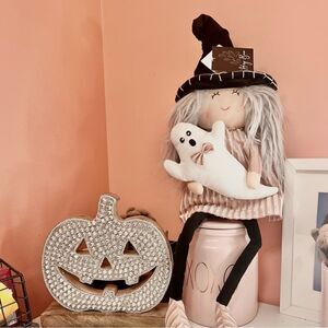 Halloween Witch in Pink Dress holding a ghost decoration.